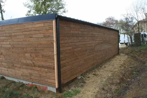 Long garage toit plat lasuré brun, vue latérale